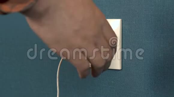 一个男人从墙上的插座里掏出一个电话充电器墙上的罗塞特和深蓝色壁纸特写视频的预览图