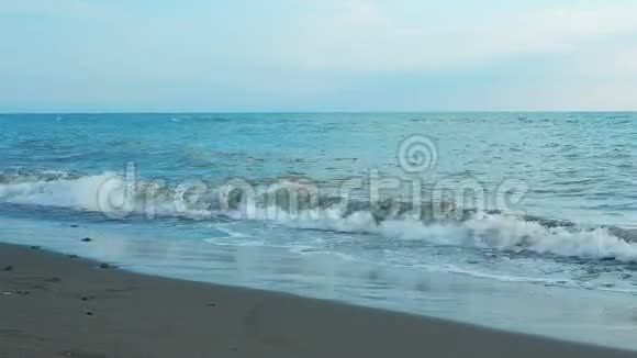 海浪在近景低角度视野慢镜头日出或蓝小时时间滚上岸视频的预览图