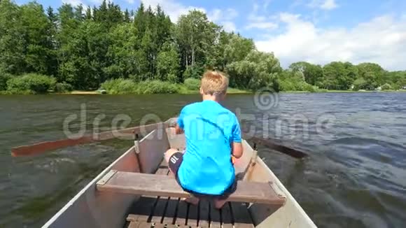 十几岁的小男孩在湖边划船或划桨蓝色的夏日天空视频的预览图