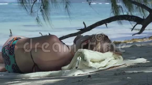 塞舌尔普拉斯林岛年轻的女孩躺在棕榈树的树荫下在异国情调的海岸听音乐视频的预览图
