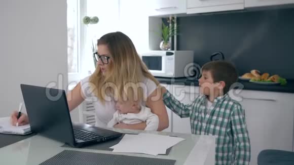 忙忙碌碌的母亲抱着孩子对着儿子尖叫儿子在家里工作视频的预览图