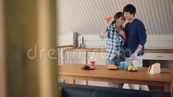 玩的年轻人在厨房里玩得很开心在家吃早餐时吃糕点和跳舞听音乐视频的预览图