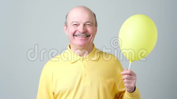 手持氦气的黄气球老人视频的预览图