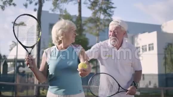 肖像快乐的成年夫妇在阳光明媚的日子打网球一个老男人和一个成熟的女人喜欢这个游戏康乐及文化事务署视频的预览图