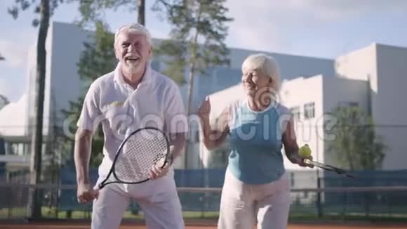 肖像快乐的成年夫妇在阳光明媚的日子打网球一个老男人和一个成熟的女人喜欢这个游戏康乐及文化事务署视频的预览图