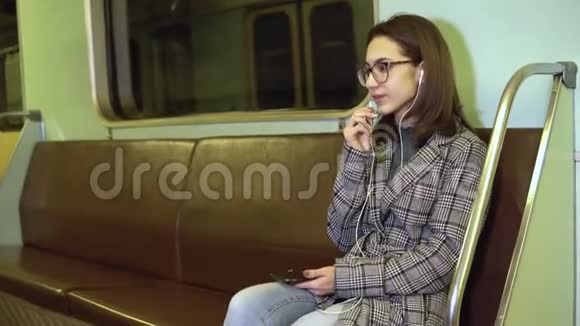 一位年轻女子正在地铁列车上通过耳机打电话旧地铁车视频的预览图