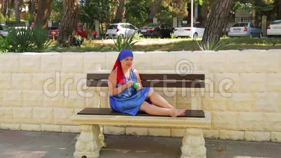 一个年轻的女人坐在公园的长凳上吃冰淇淋视频的预览图