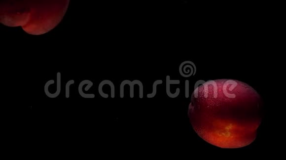 两个熟透的桃子在黑底透明的水底下视频的预览图