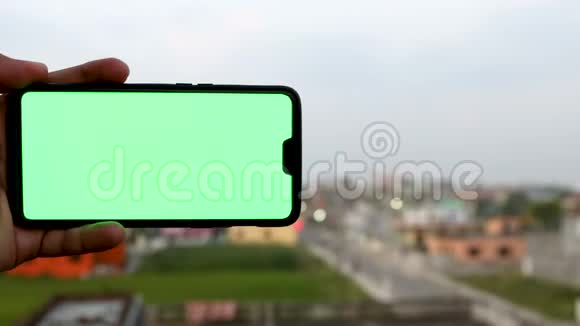 一个拿着绿色屏幕的智能手机的男人的镜头视频的预览图