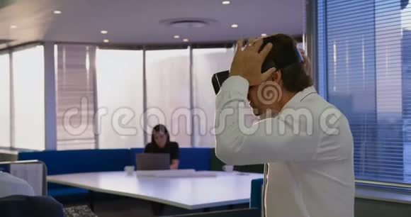 年轻的高加索男性高管戴着虚拟现实耳机在现代办公室的侧视4k视频的预览图