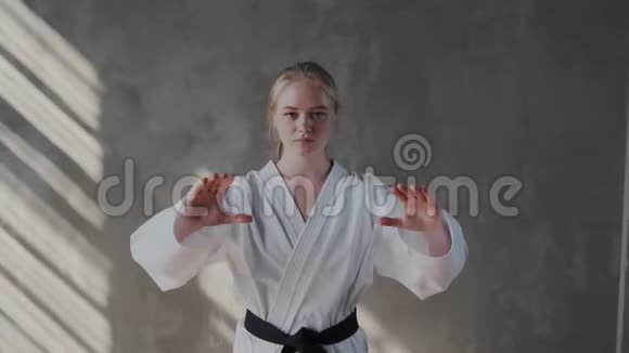 一个女孩表演传统的跆拳道姿势她的双臂张开张开手掌看着镜头视频的预览图