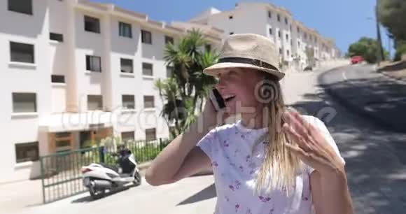 一个戴帽子的女人在西班牙的一个度假胜地用手机说话视频的预览图