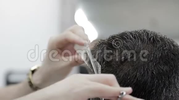 男人理发店理发一个用剪刀剪黑发的人的特写视频的预览图