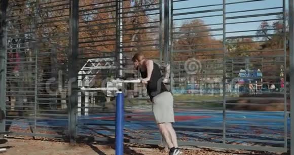 有吸引力的运动员在户外健身房训练前臂二头肌和三头肌他在城市公园训练年轻英俊视频的预览图