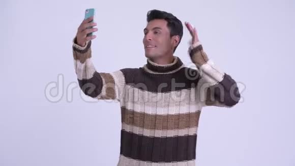 年轻快乐的西班牙男子视频通话和显示电话准备过冬视频的预览图