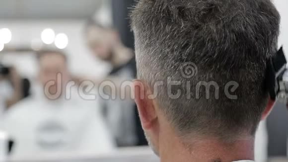 男人理发店理发大师用剪刀剪一个黑发的人的特写视频的预览图