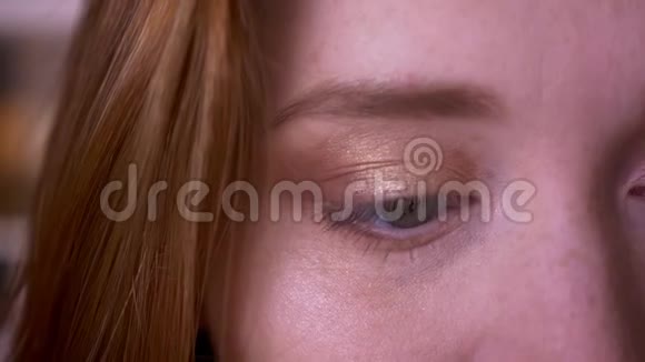 在学院里一位年轻的红头发迷人的白种人女性用眼睛看着镜头特写半张脸的肖像视频的预览图