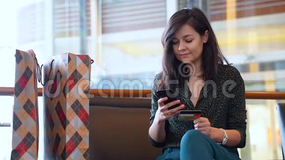 使用信用卡和电话进行网上购物的年轻妇女视频的预览图