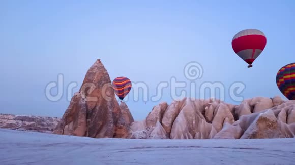 在土耳其卡帕多西亚空中观看热气球运动的童话烟囱覆盖着雪视频的预览图