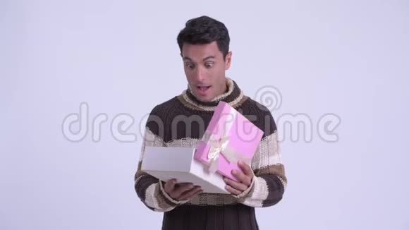 年轻快乐的西班牙男人打开礼物盒看上去很惊讶地准备过冬视频的预览图