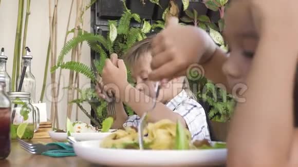 孩子们在夏季餐厅吃午餐可爱的男孩和女孩在儿童餐厅吃健康的食物小女孩和视频的预览图
