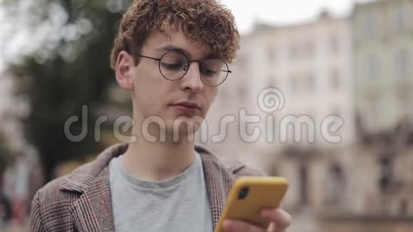 用他的现代手机应用程序看屏幕喝咖啡特写眼镜中严肃千禧年的肖像视频的预览图