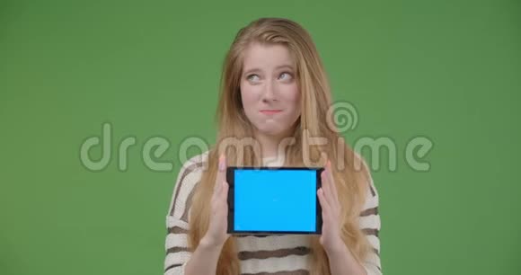 用平板电脑拍摄年轻漂亮的白种人女性的特写镜头用蓝色屏幕拍摄欢快地微笑视频的预览图