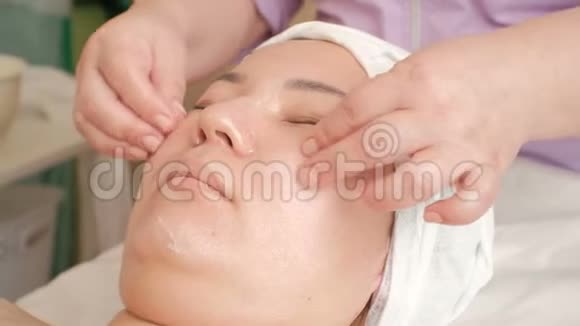 一个亚洲女孩在美容院的特写面部按摩美容师的双手进行皮肤修复视频的预览图