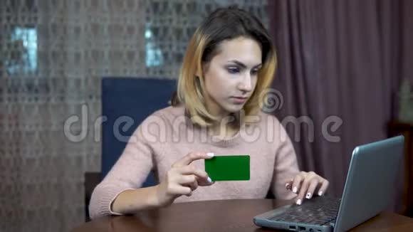 有信用卡和笔记本电脑的女孩将卡片数据填充到笔记本电脑中绿色屏幕视频的预览图