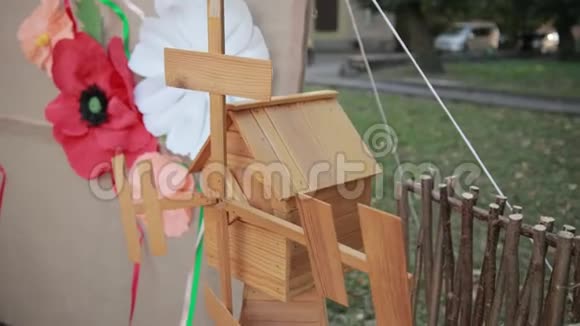 小木风车矗立在栅栏附近靠近画布上装饰的花朵视频的预览图