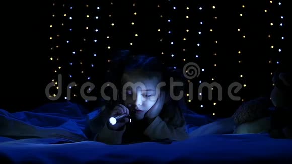 小女孩躺在床上用手电筒照她读的书博克背景慢动作视频的预览图
