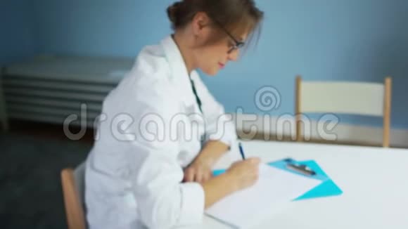 戴着白大褂和眼镜的儿科医生为坐在办公桌前的病人开处方视频的预览图