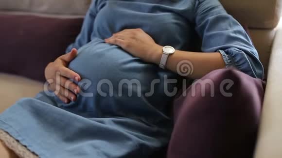 孕妇坐在床上抚摸腹部视频的预览图