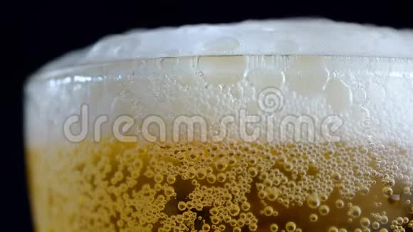 宏观慢镜头拍摄将啤酒倒入玻璃杯中直到啤酒在玻璃杯上气泡视频的预览图
