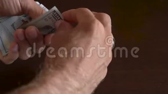 一个商人手里拿着100美元钞票的特写镜头视频的预览图