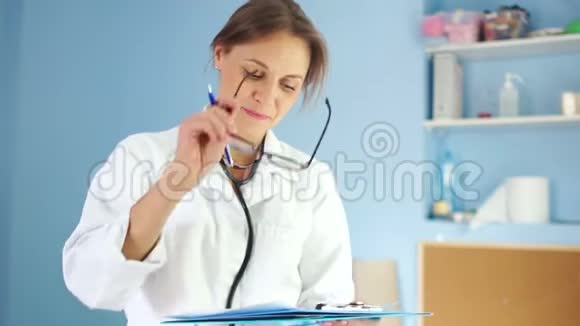 戴眼镜和白大褂的严格的女医生在他的办公室里开了一张处方国际医生日视频的预览图