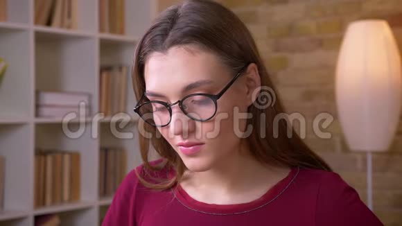 年轻的黑发长发女学生戴着眼镜的特写镜头平静地注视着镜头视频的预览图