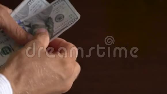 一个商人手里拿着100美元钞票的特写镜头视频的预览图