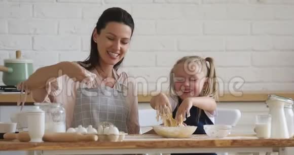 可爱的小女儿在厨房和妈妈一起学习揉面视频的预览图