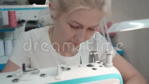 车间电动机器上缝制衣服的女青年视频视频的预览图