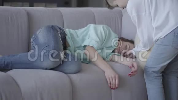 这位年轻的母亲在家睡着了十几岁的儿子把枕头放在女人的头下面然后躺在沙发上靠近妈妈女人是视频的预览图