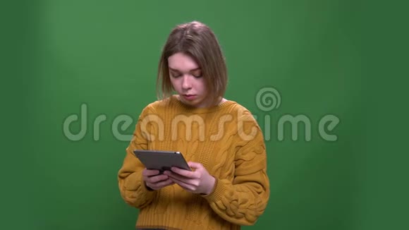 年轻有吸引力的短毛女性的特写镜头使用绿色背景的平板电脑视频的预览图