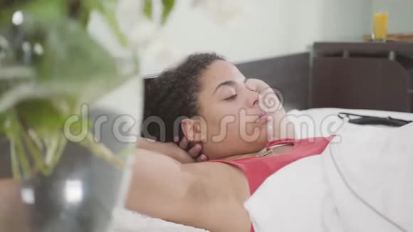 可爱的非裔美国女人躺在床上可爱的女孩在家放松离开这位女士视频的预览图
