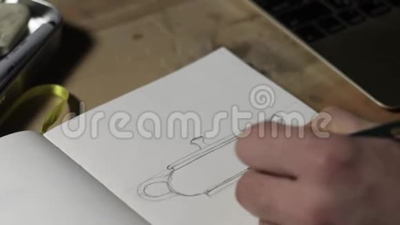 特写一个男手在纸上画一个泥茶壶素描男性用铅笔画画宏观视野4k录像5994fps视频的预览图