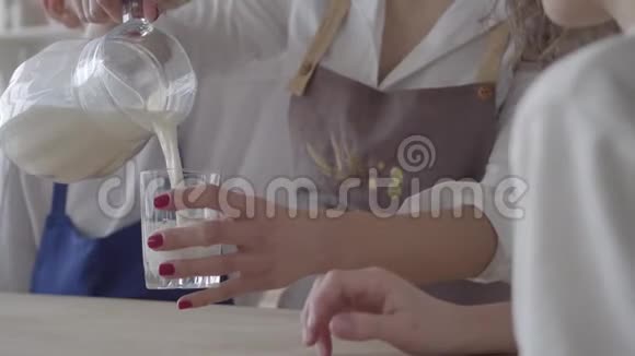 无法辨认的女人把牛奶倒在玻璃杯里然后送给她的儿子穿围裙的女士关心孩子健康生活方式视频的预览图