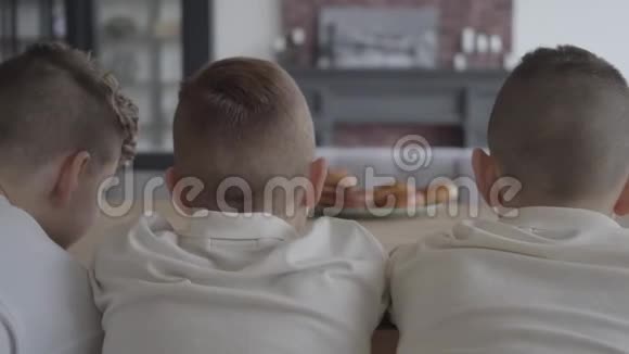 前景中的三个男孩看着模糊的盘子桌上摆着美味的小馅饼视频的预览图