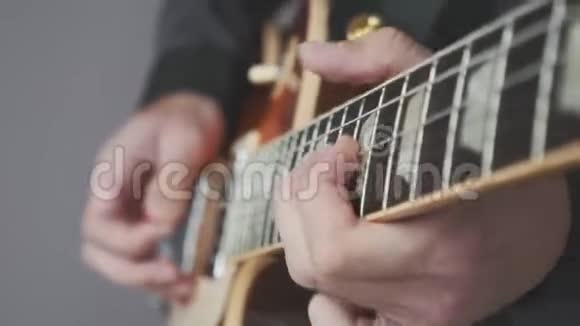 男手在电吉他上弹得很近手指在吉他微动板上拿着镐演奏和弦和独奏音乐表演视频的预览图
