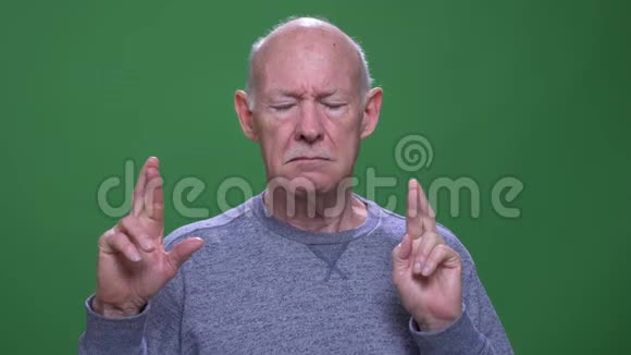 一个老高白种人的特写镜头他的手指交叉着希望看着背景的摄像机视频的预览图