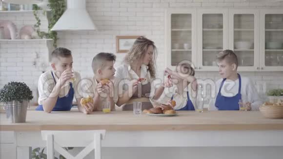 她和四个十几岁的儿子站在凯特肯身边一边吃馅饼一边喝橙汁视频的预览图
