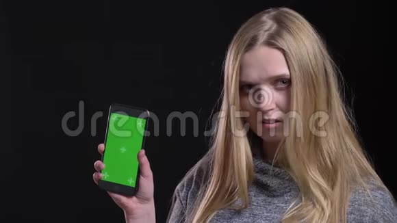 金发女孩演示绿色屏幕的智能手机以建议应用程序认真的黑色背景视频的预览图